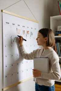 iño de 10-11 años frente a un calendario grande colgado en la pared